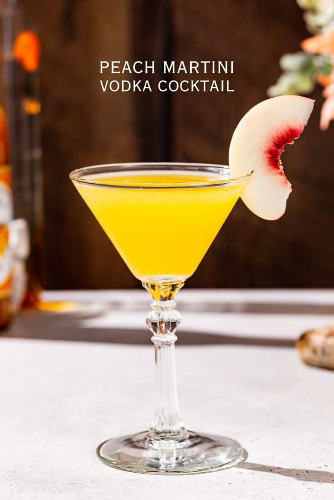 Side view of a Peach Martini vodka cocktail, garnished with a peach slice on the rim of the glass. Text above the drink says “Peach Martini vodka cocktail”.