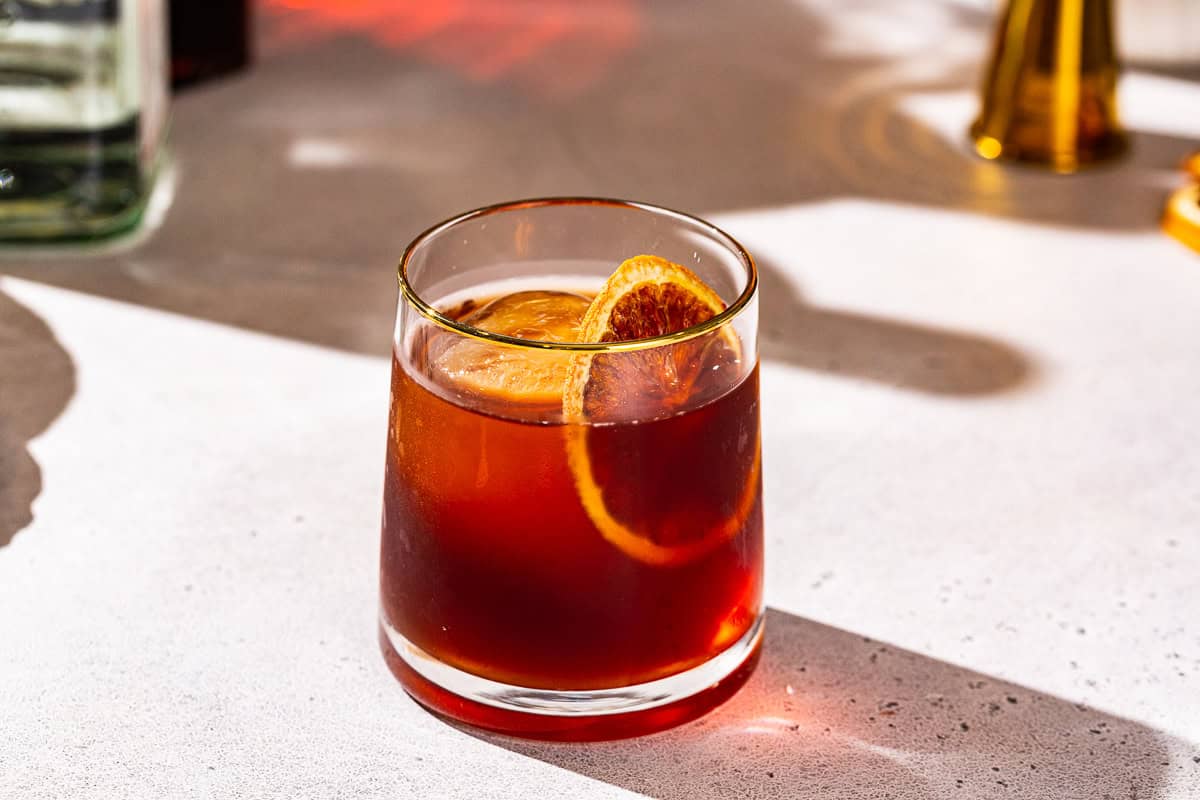 Coffee Negroni cocktail in an old fashioned style glass, garnished with a dried orange slice.