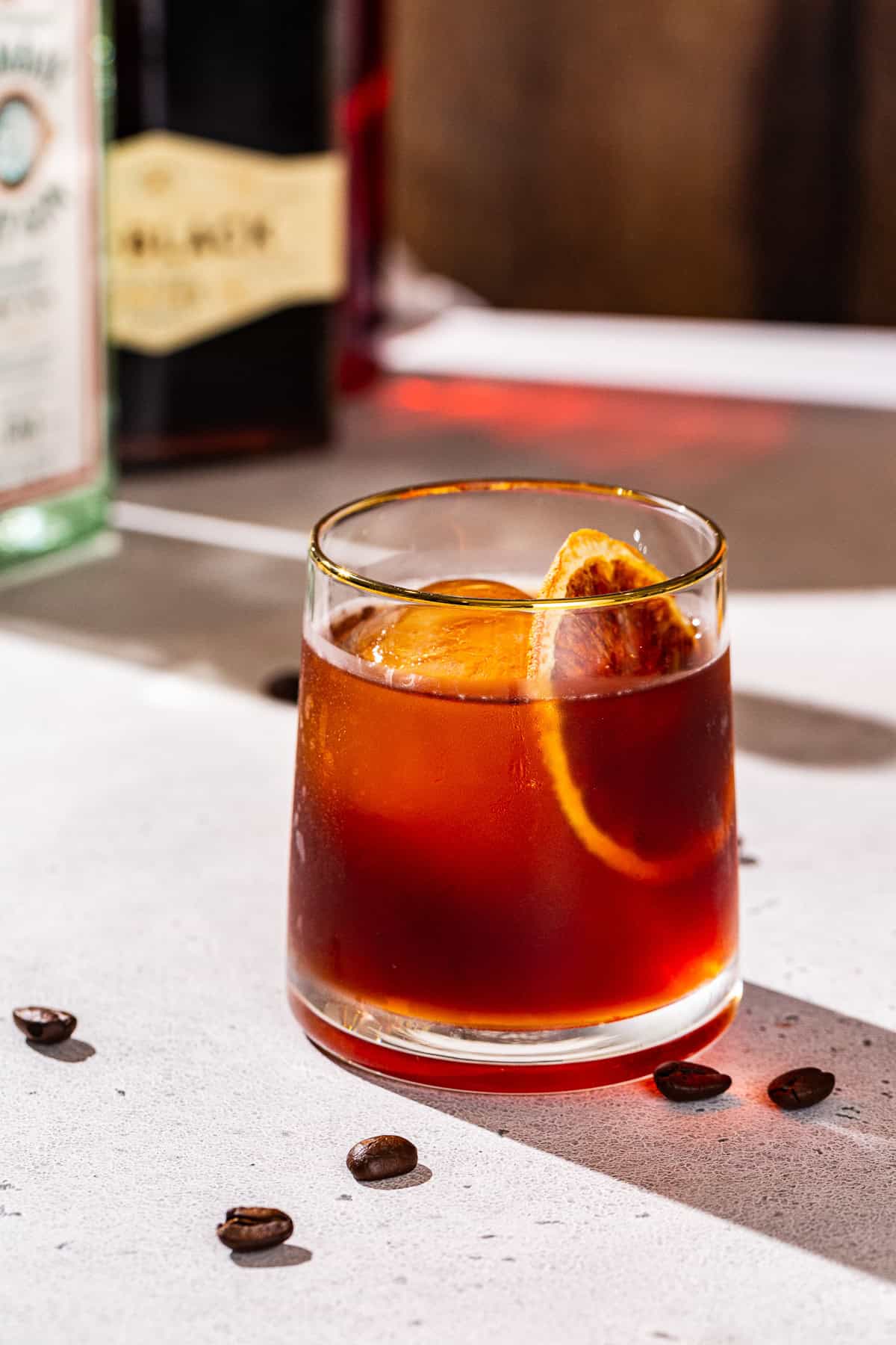 Coffee Negroni on a countertop with bottles used to make the drink in the background.