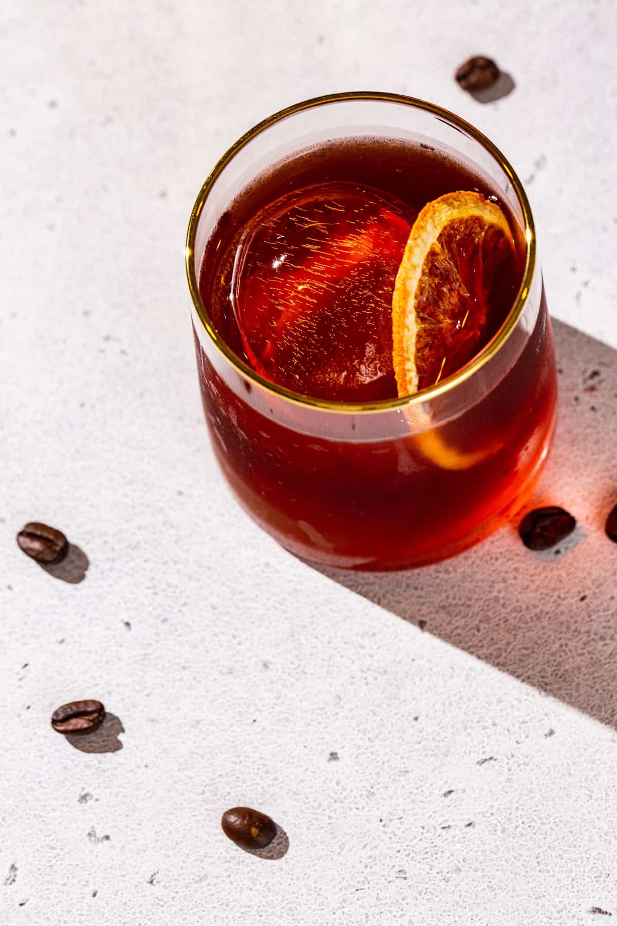 Overhead view of a Coffee Negroni with some cofee beans on the table around it.