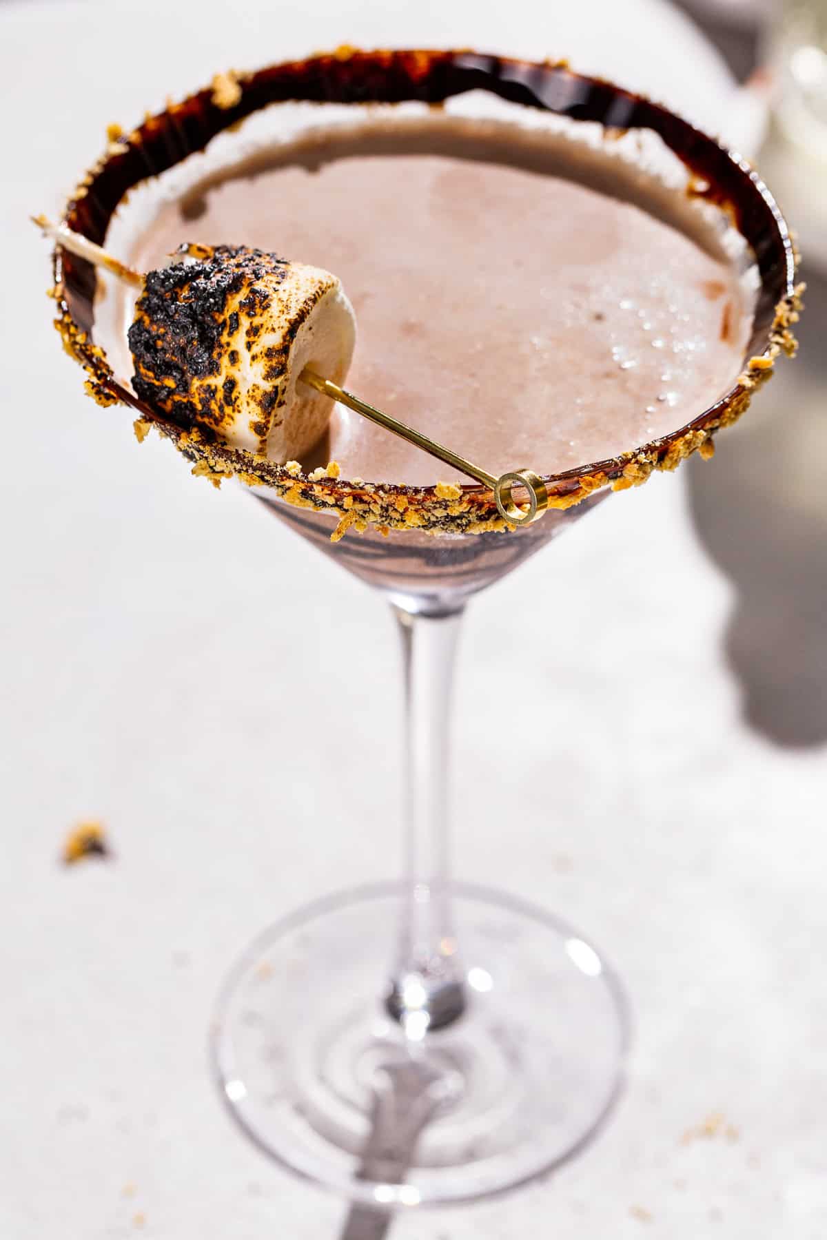 Smores martini, garnished with a toasted marshmallow, chocolate syrup and graham cracker crumbs.