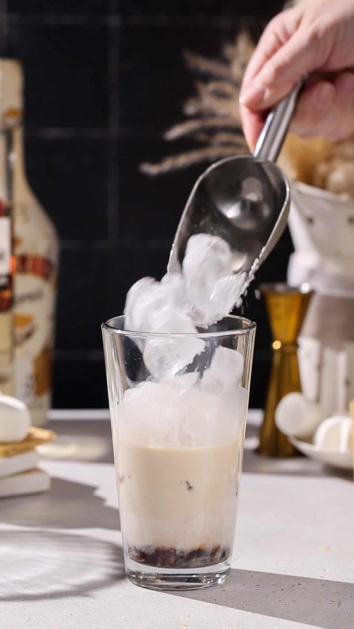 Hand adding ice to a cocktail shaker.