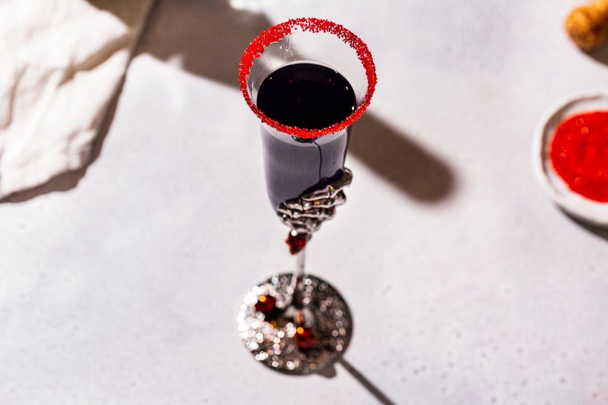 Overhead view of a Black Mimosa cocktail with a red sugar rim.