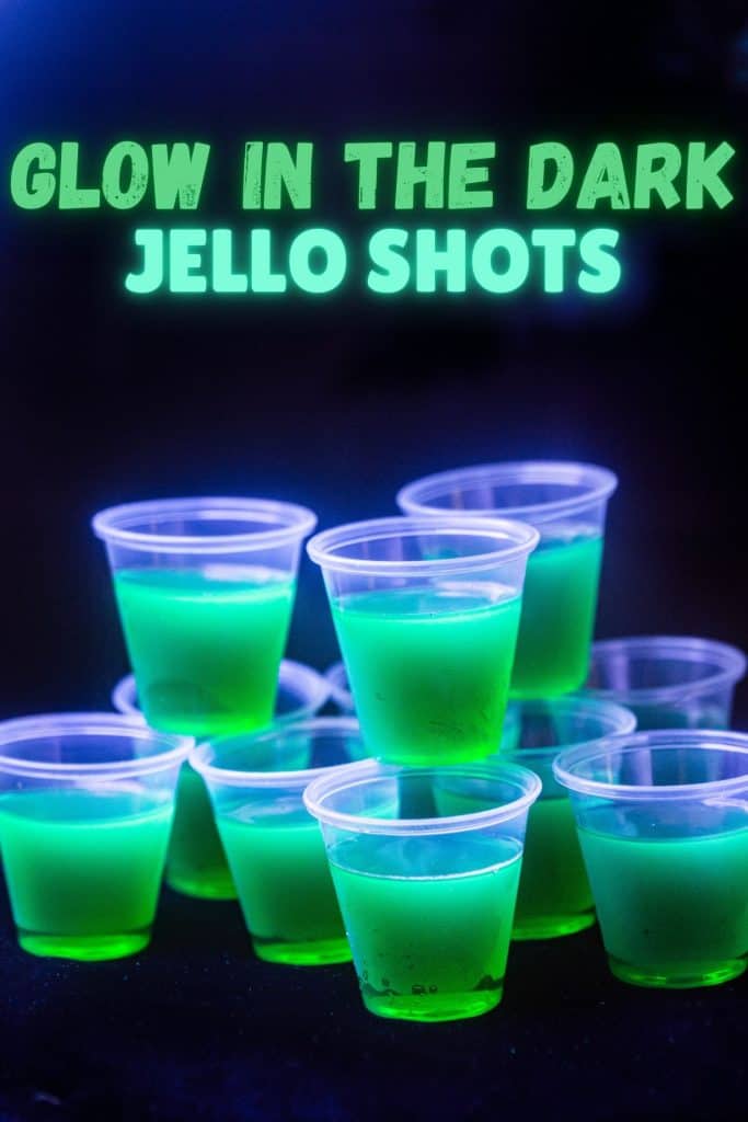 Glow in the dark jello shots shown glowing under UV light from a blacklight. Bright green text above the shots says “Glow in the dark Jello shots”.