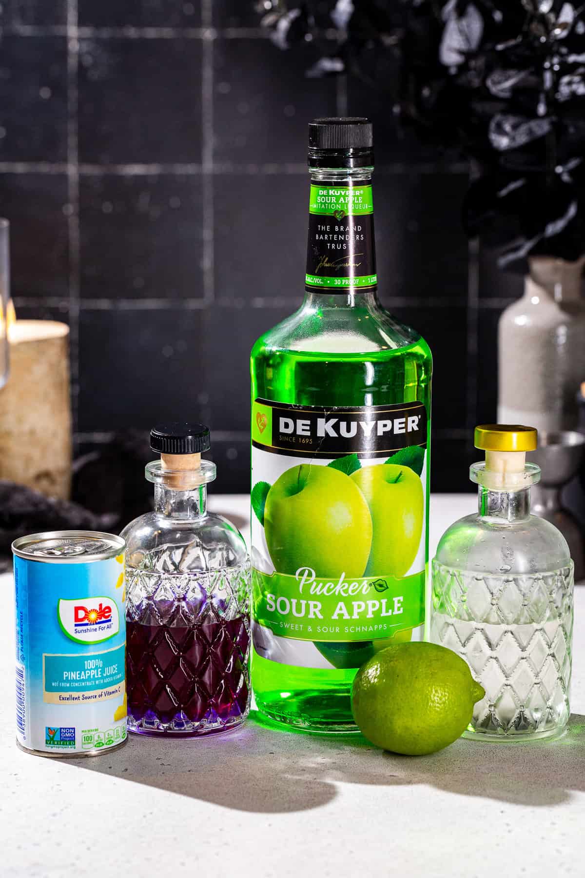 Ingredients to make a Witches’ Brew Halloween cocktail together on a countertop.