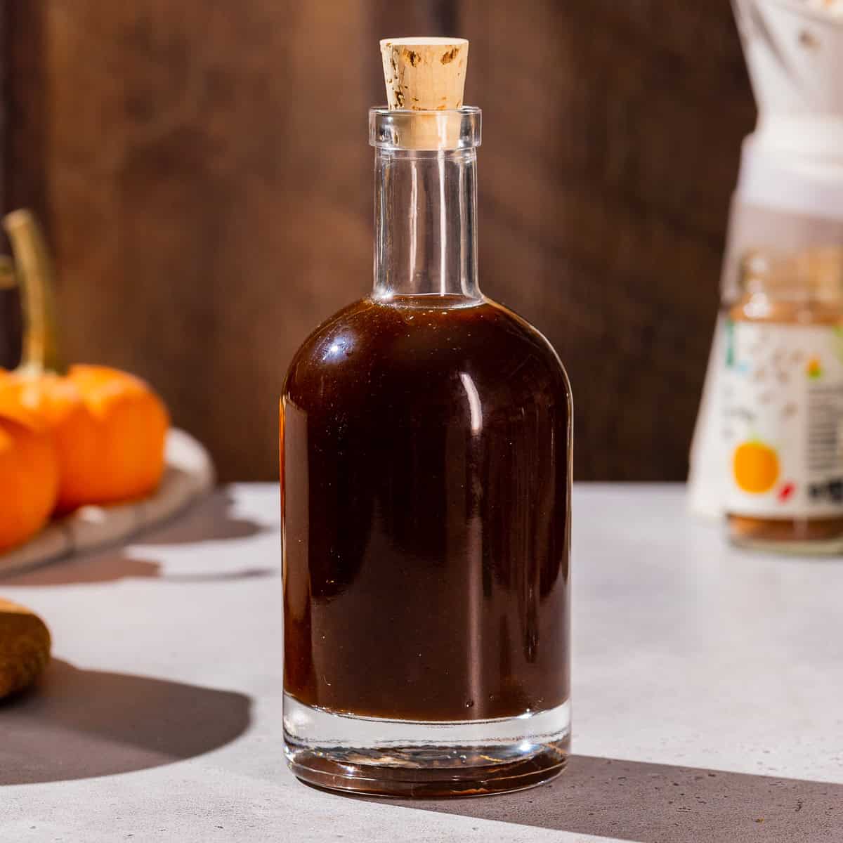 Close up of a bottle of Pumpkin Spice syrup. The syrup is brown in color and the bottle has a cork stopper.