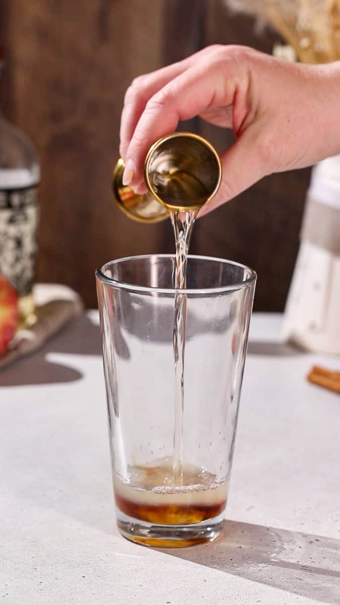 Hand pouring cointreau liqueur into a cocktail shaker.