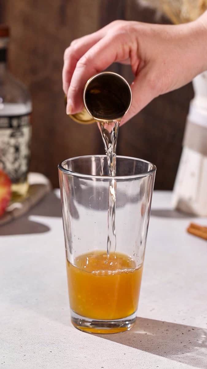 Hand adding tequila to a cocktail shaker.