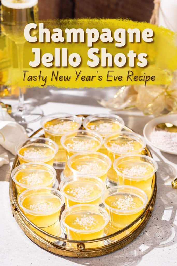 A tray full of cups of Champagne Jello Shots sits on a countertop. Gold decor is in the background. A text overlay above the jello shots says “Champagne Jello Shots - tasty New Year’s Eve Recipe”.