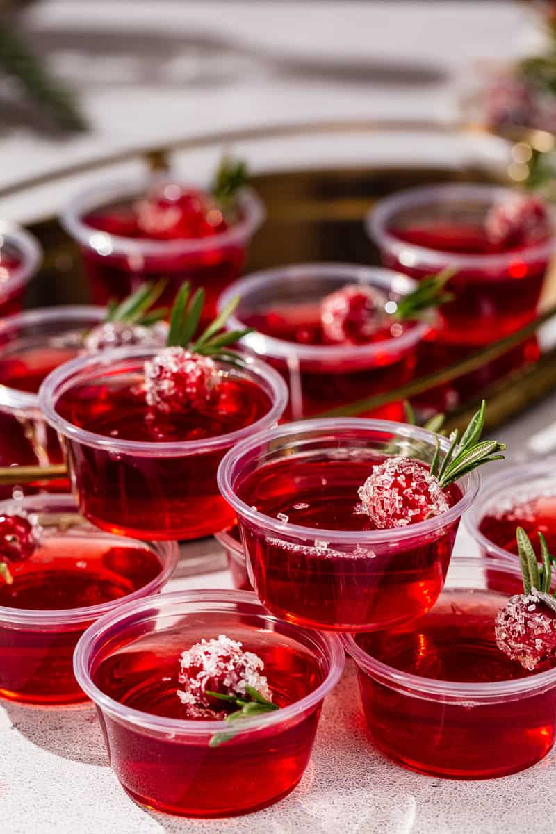 Cranberry Christmas Jello Shots with sugared cranberries and fresh rosemary garnishes.