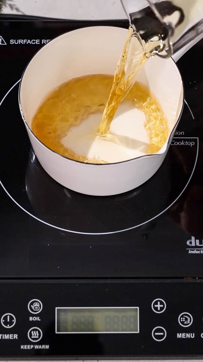 Hand pouring apple juice into a saucepan.