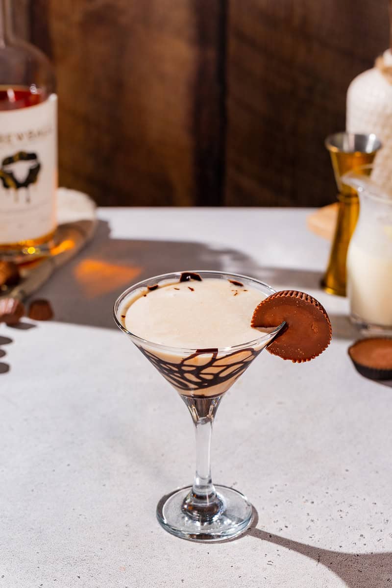 Peanut Butter Cup Martini on a countertop with some ingredients and bar tools in the background.