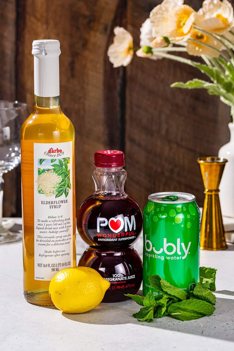 Ingredients to make a Pomegranate Spritzer Mocktail together on a countertop.