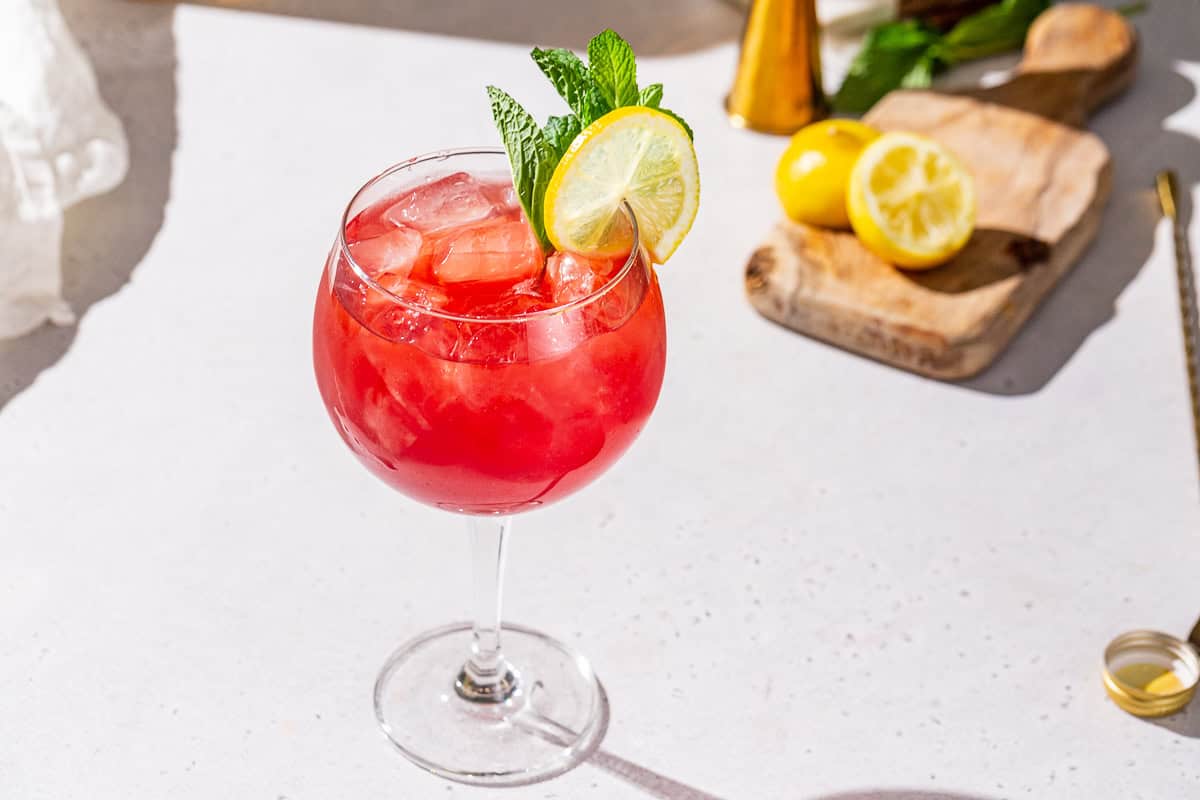 Pomegranate Spritzer Mocktail on a white countertop with lemons in the background.