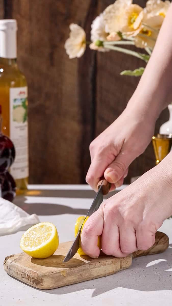 Hands cutting a lemon slice.