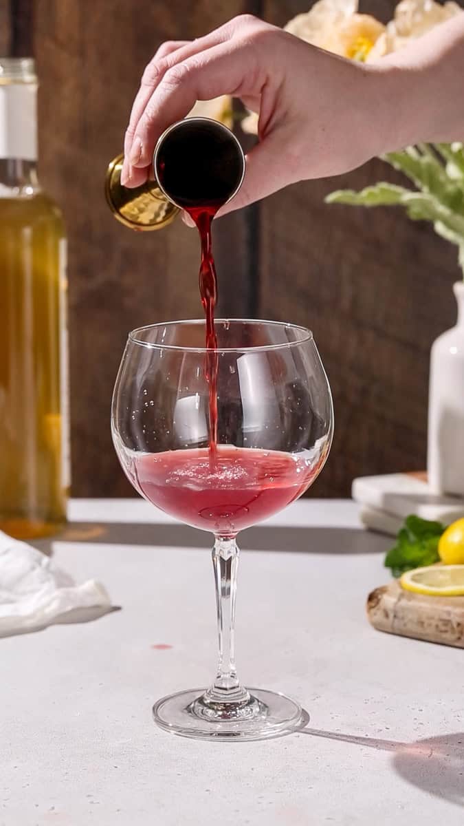 Hand pouring pomegranate juice into a glass.