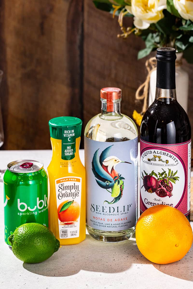 Ingredients to make a tequila sunrise mocktail together on a countertop.