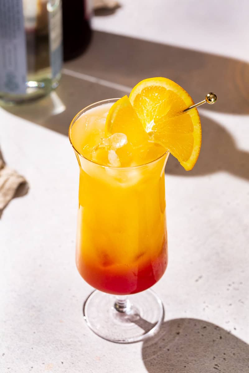 Tequila Sunrise Mocktail garnished with an orange slice on a cocktail pick.