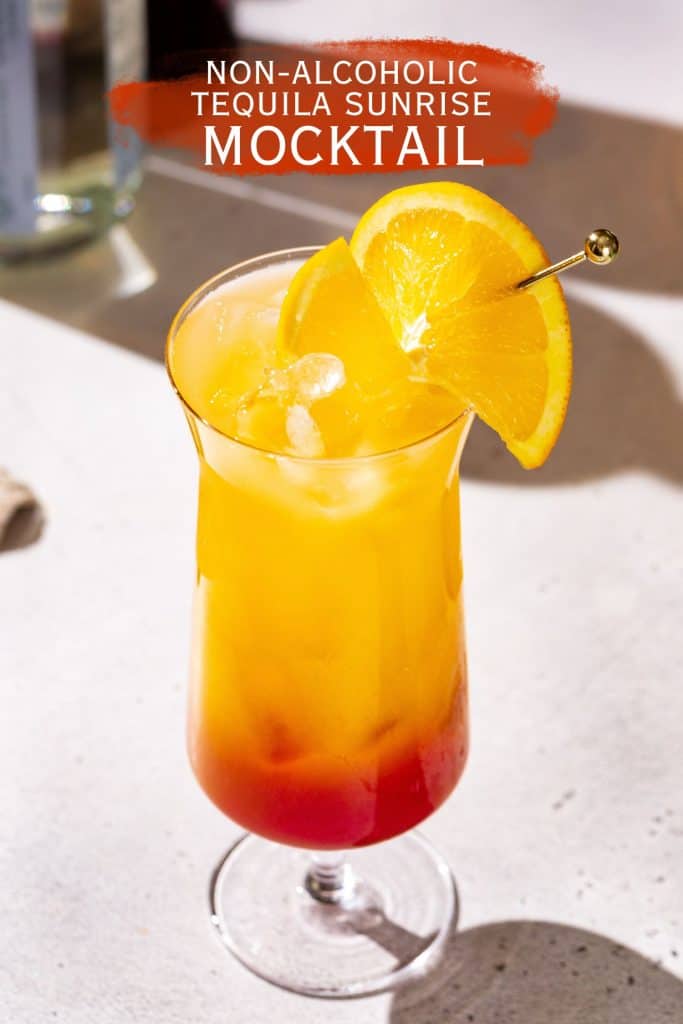 Overhead view of a Tequila Sunrise Mocktail in a hurricane style cocktail glass. Text above the drink says “Non-alcoholic Tequila Sunrise Mocktail”.