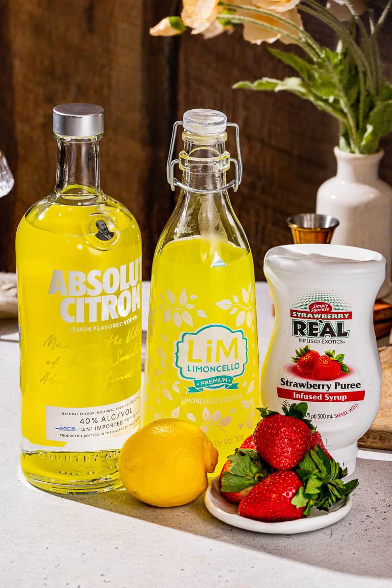 Ingredients to make a Strawberry Lemon Martini together on a countertop.